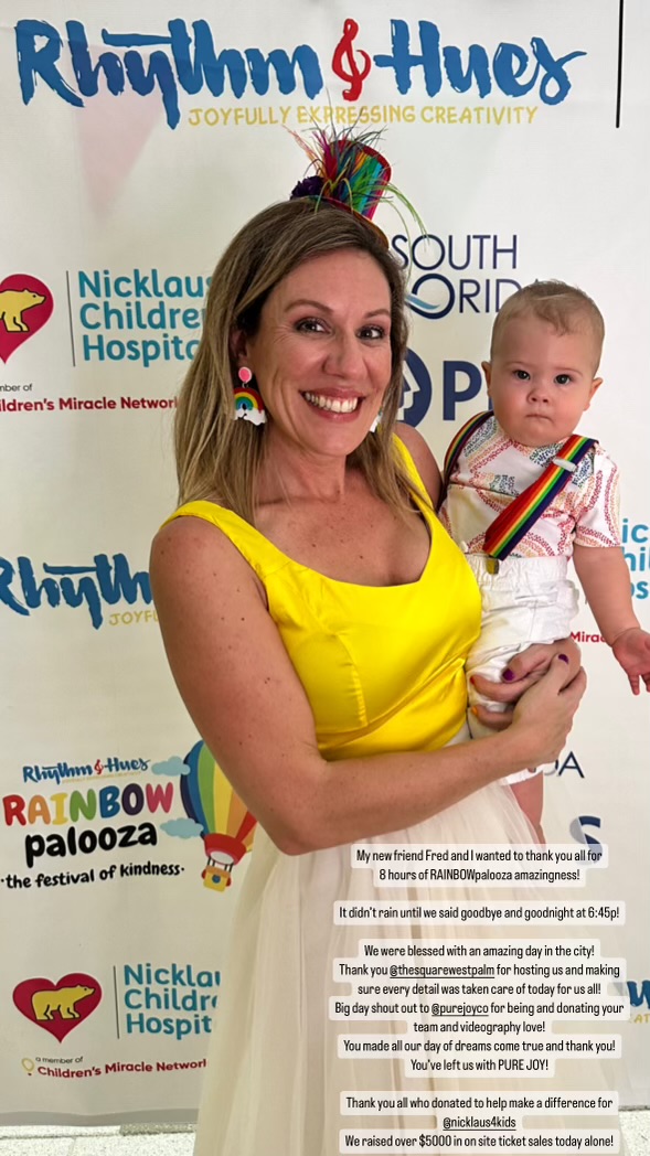 CJ Valle holding a child at a RAINBOWpalooza community event
